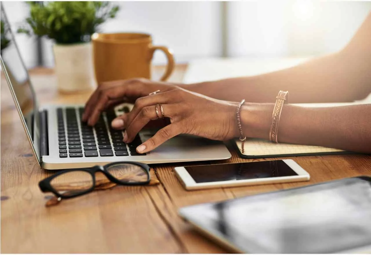 a picture of a woman's hands typing and working with a laptop sending transactional emails