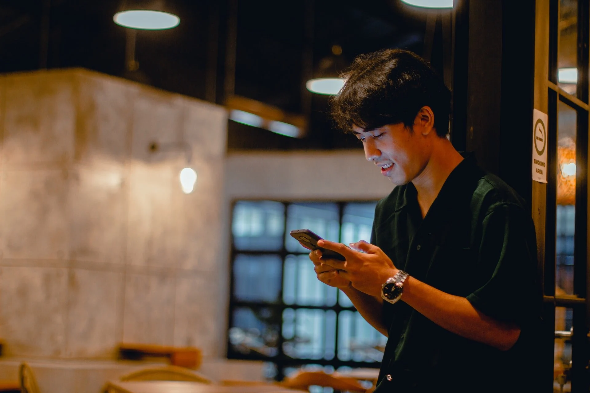 un homme envoyant des SMS avec un téléphone portable et souriant