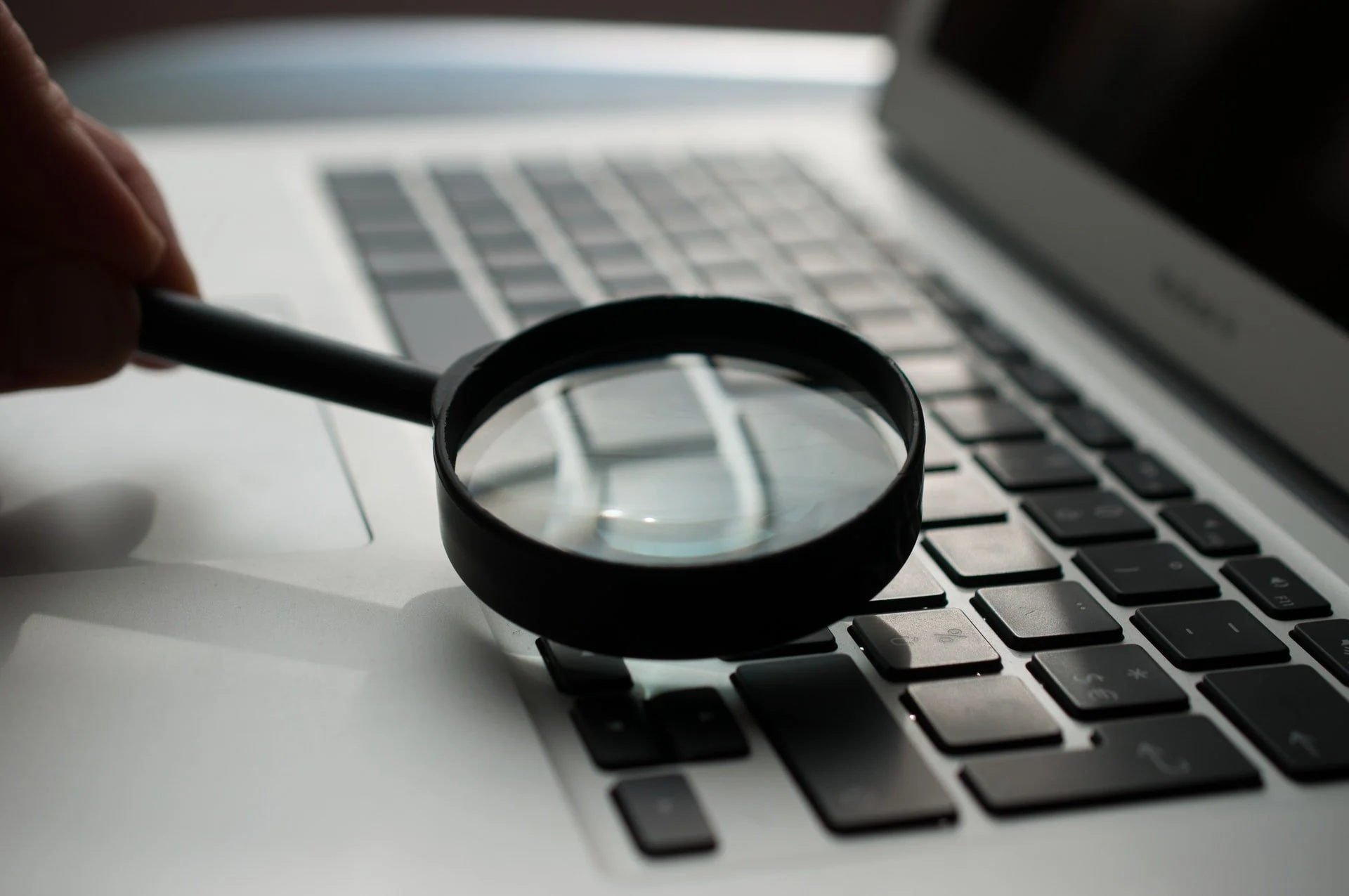 a person putting a magnifying glass to a MacBook Air