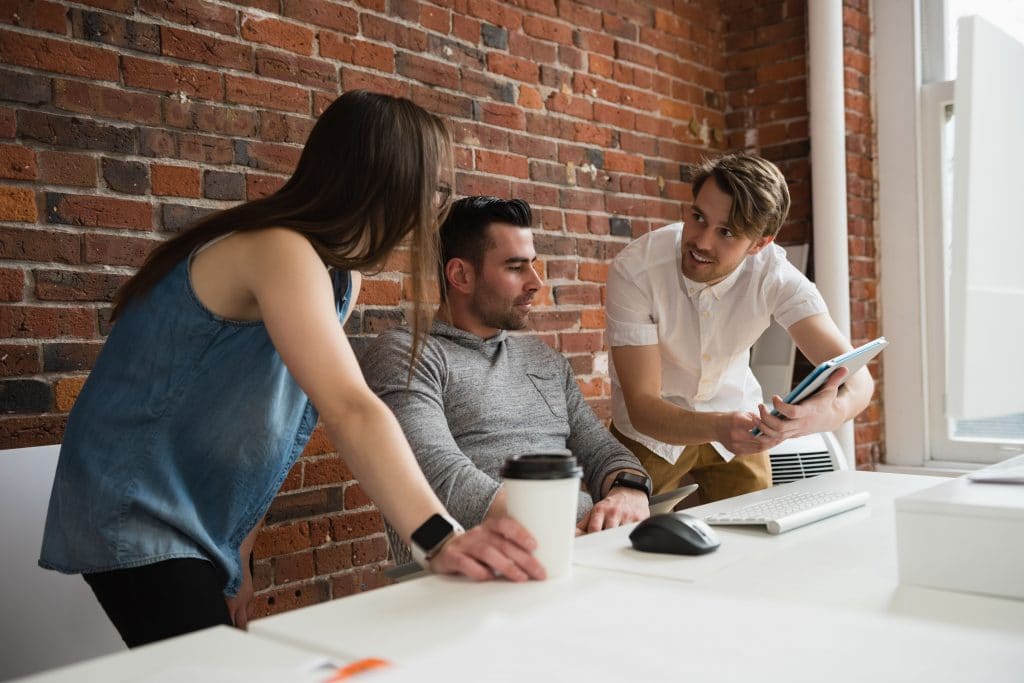 tiga orang sedang rapat di kantor