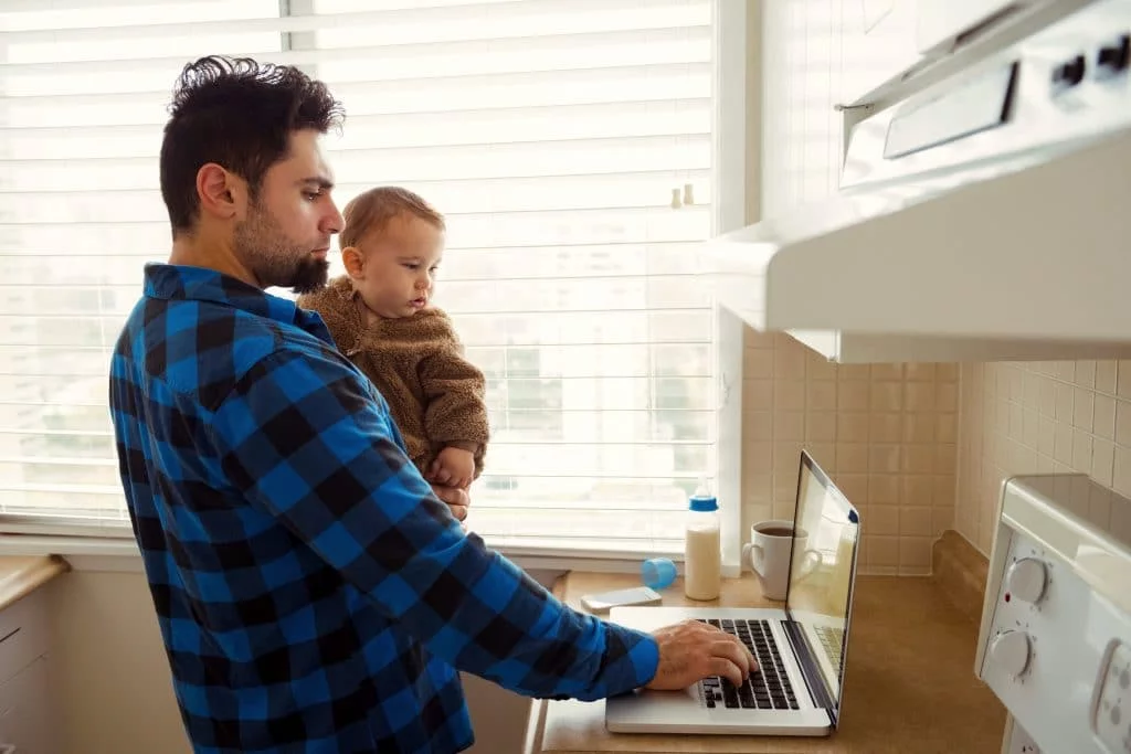 hombre sosteniendo a un niño mirando la computadora