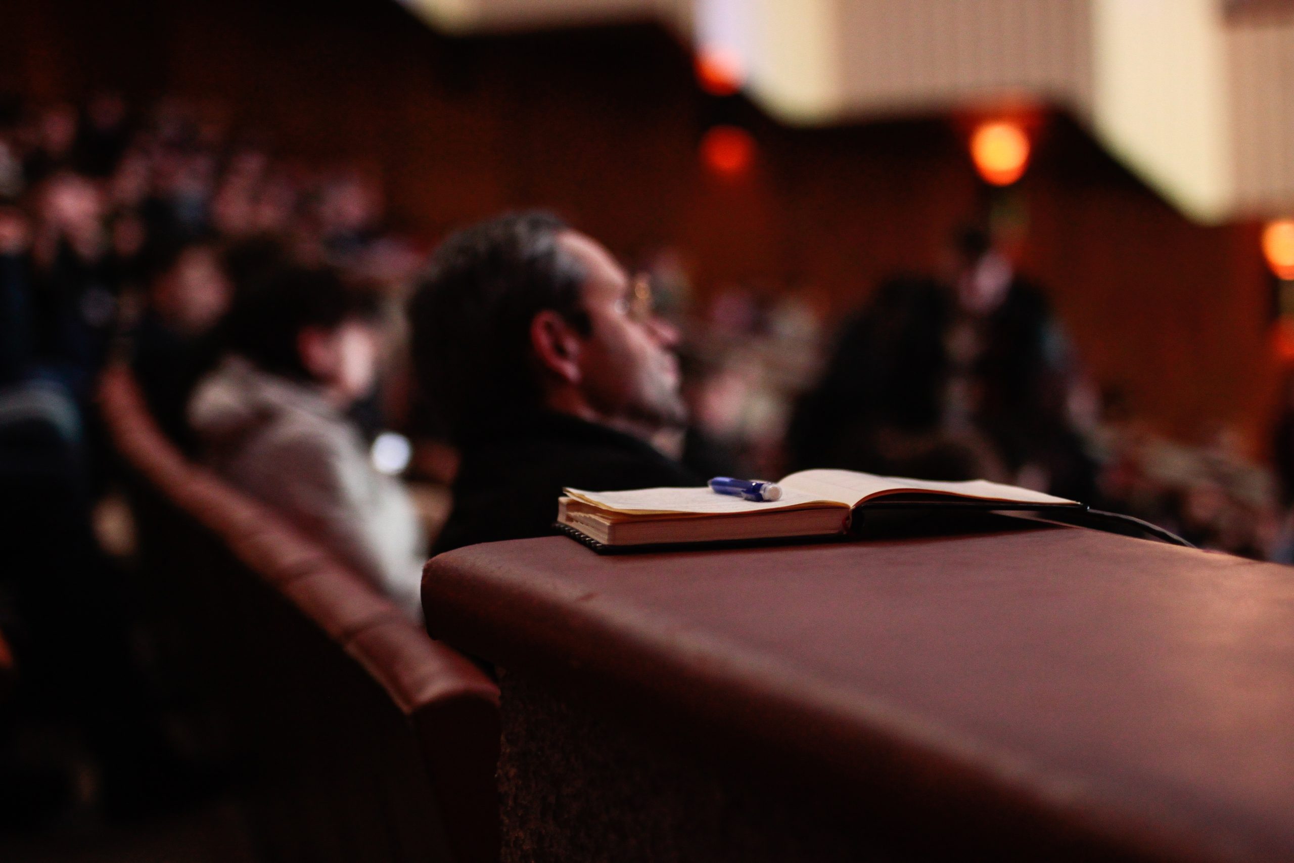 Audiencia escuchando con un libro en el foco principal