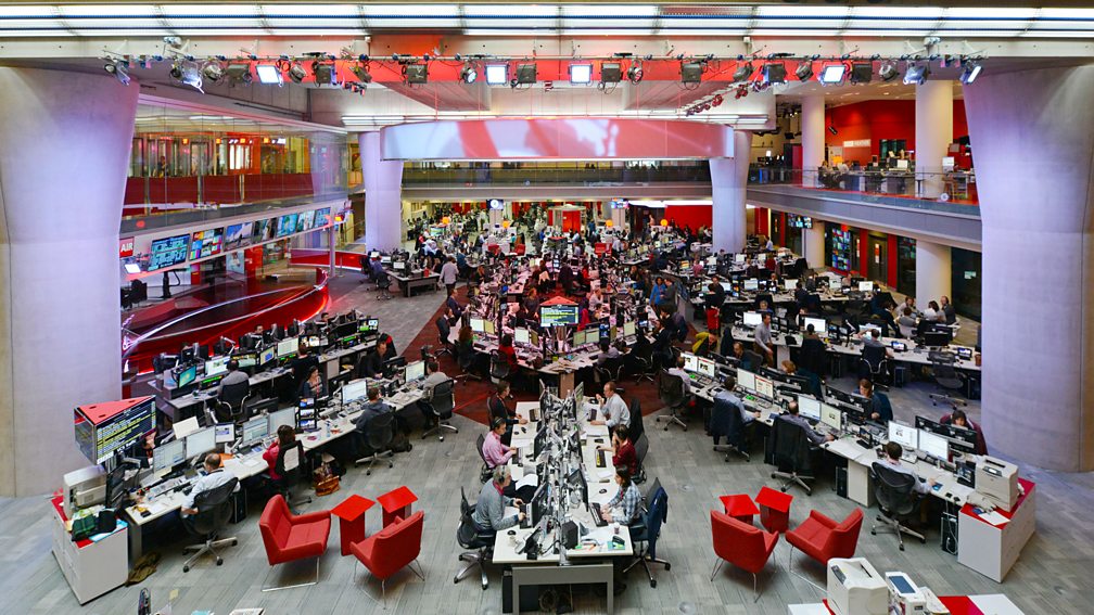 The large news room at the BBC, filled with desks and journalists.