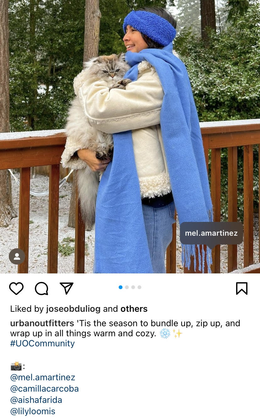 A girl is wearing Urban Outfitters accessories and holding a cat, smiling. The brand has hash-tagged "UOCommunity", which is where they get their UGC.