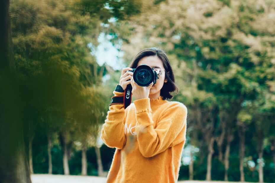 Una donna che tiene in mano una macchina fotografica e scatta una foto