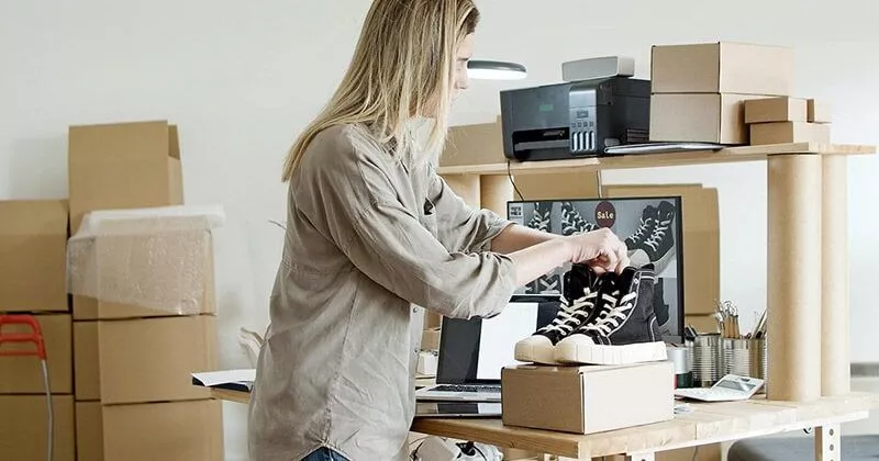 Femme tenant des chaussures achetées sur un site de commerce électronique.