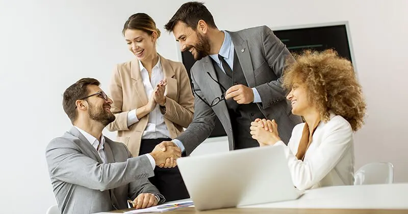 Professionisti aziendali che si stringono la mano durante una riunione.