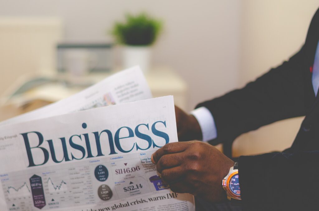 Close das mãos de um executivo negro lendo a seção de negócios de um jornal para ilustrar as táticas de ABM.