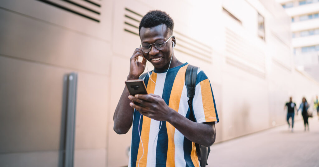 Un cliente felice, un uomo di colore, controlla la posta elettronica sul suo smartphone.