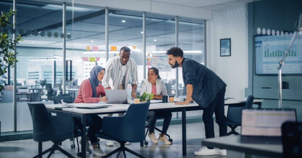 Eine vielfältige B2B-Marketingabteilung bespricht an einem großen Konferenztisch die Struktur ihres Teams.