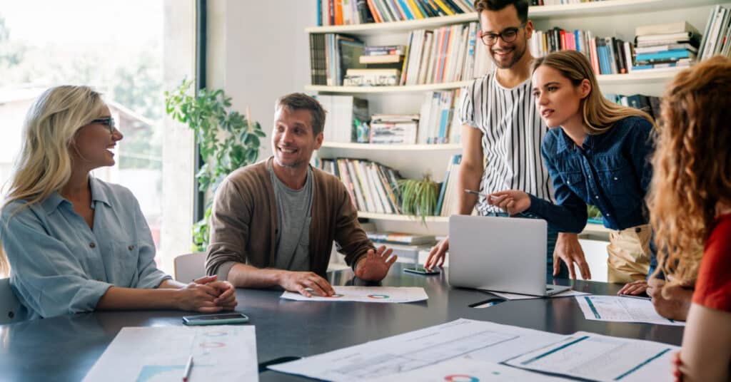 un gruppo di colleghi collabora in uno spazio ufficio moderno illustrando l'idea del ROI dell'automazione del marketing