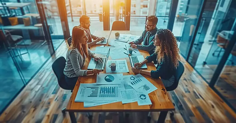 Profesionales trabajando juntos y elaborando estrategias alrededor de una gran mesa de conferencias.