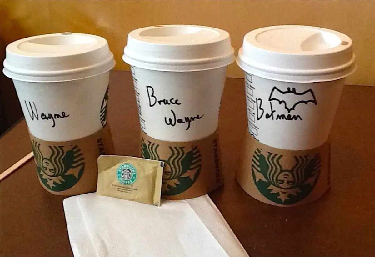 Três copos Starbucks com os nomes "Wayne", "Bruce Wayne" e "Batman"