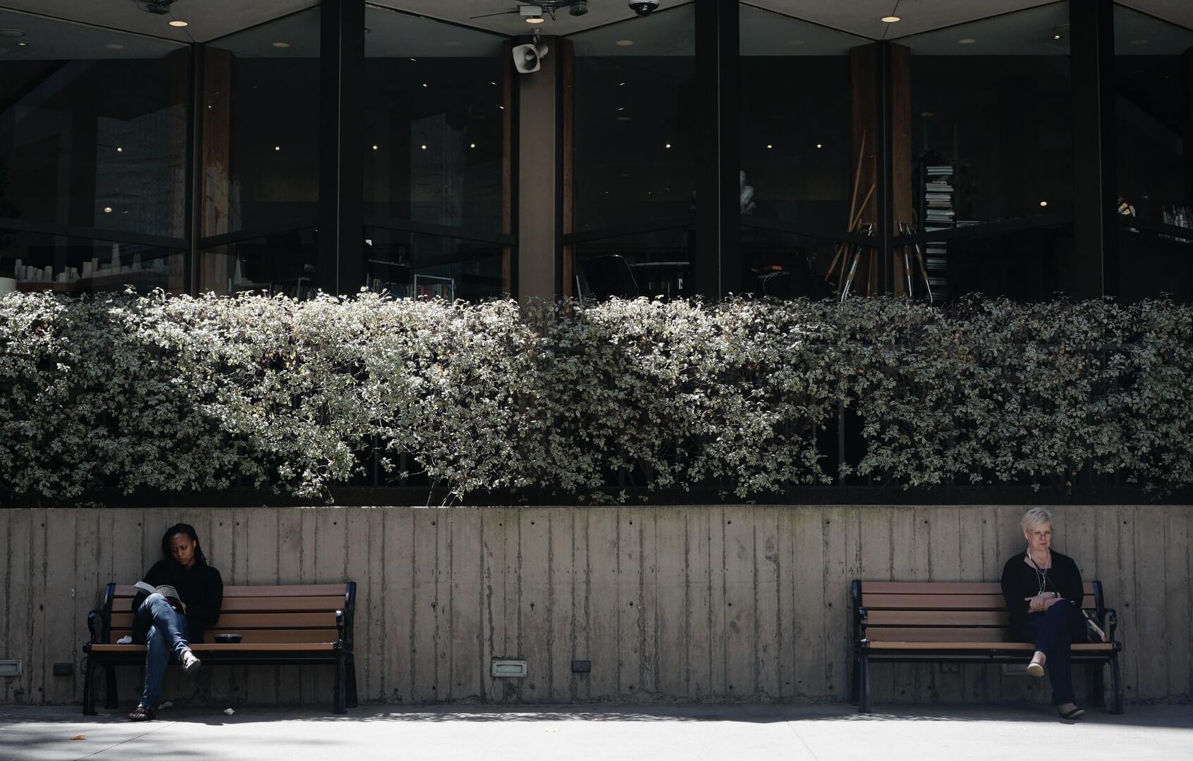 Two women sit on separate benches