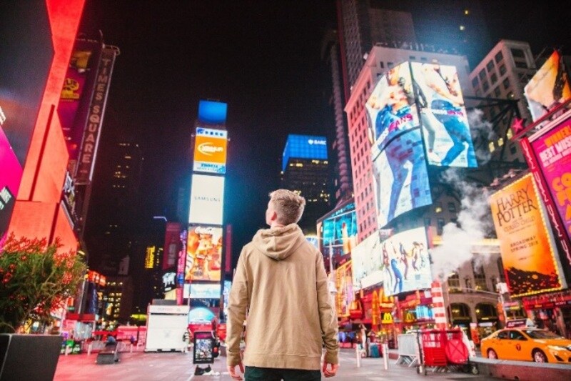 Persona a Times Square circondata da cartelloni pubblicitari immagine stock