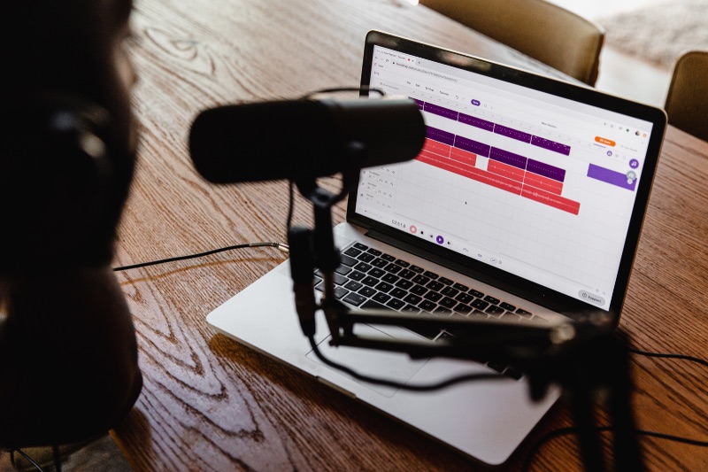 Persona che crea registrazioni di podcast con microfono e laptop DAW