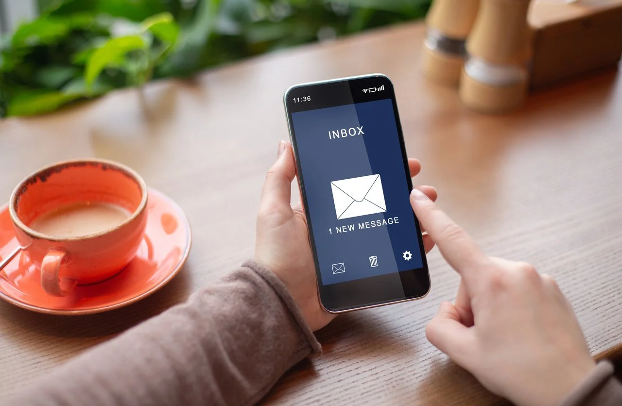 mujer sosteniendo su móvil leyendo un nuevo mensaje de correo electrónico