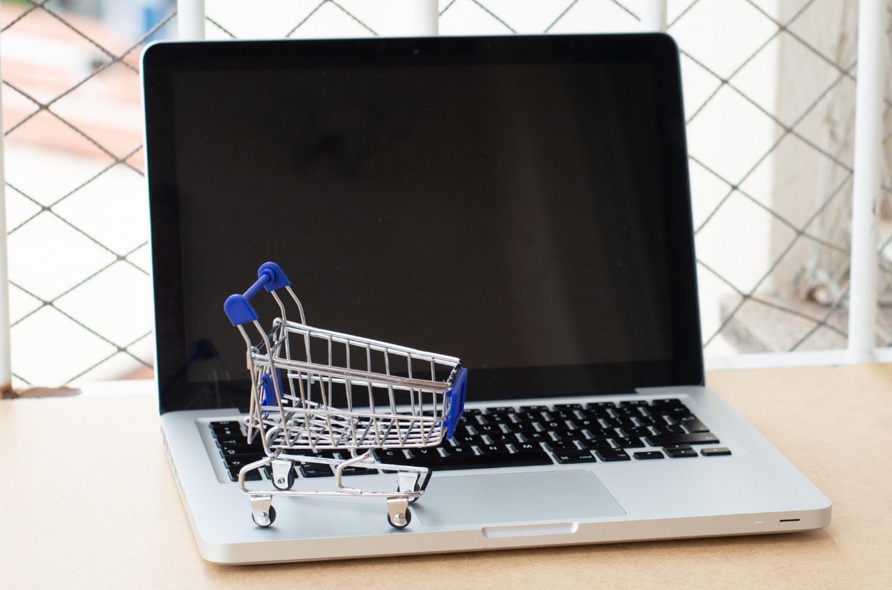 carrito de compras en miniatura en el teclado de la computadora portátil