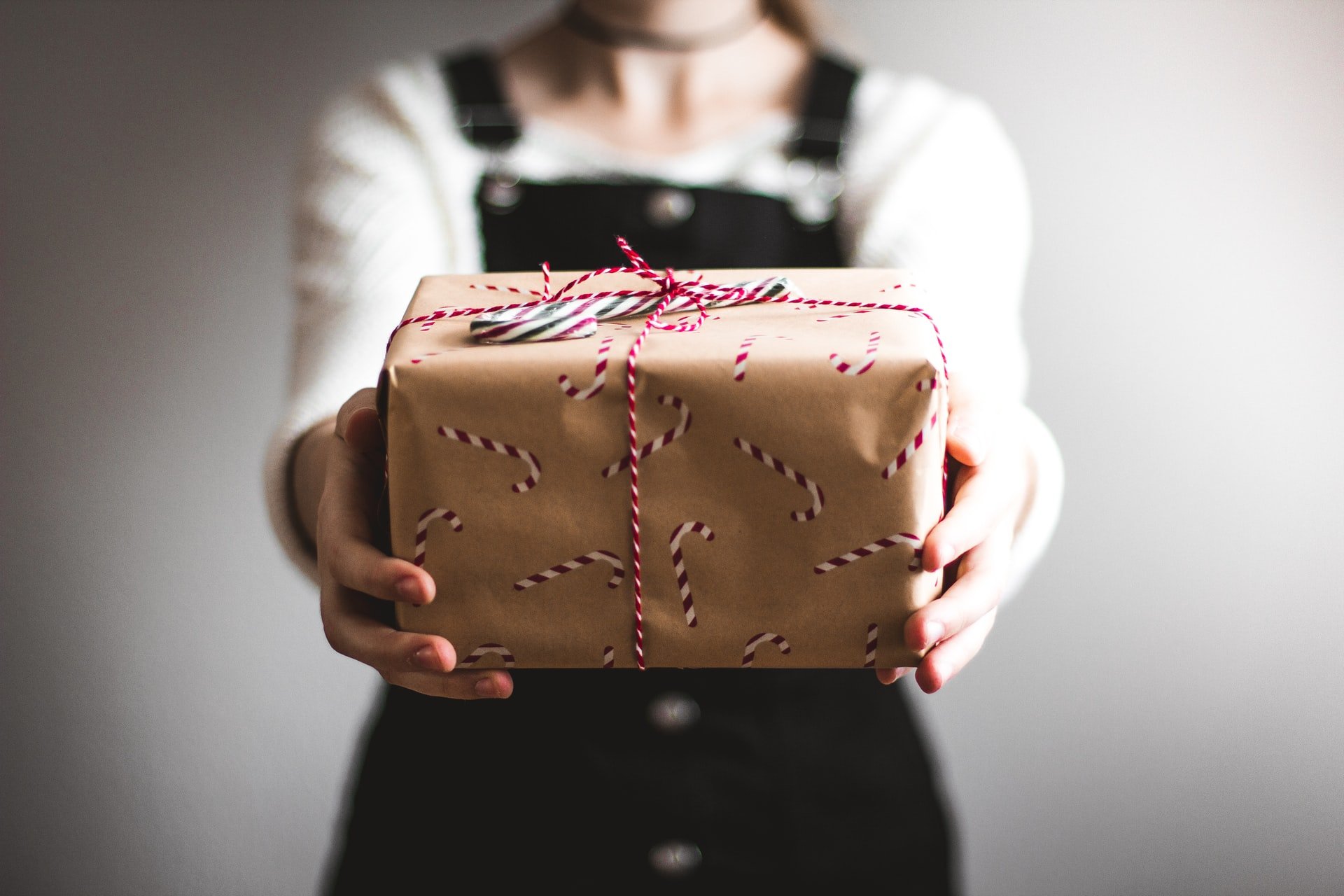 una ragazza che indossa una tuta che mostra una confezione regalo marrone con decorazioni natalizie