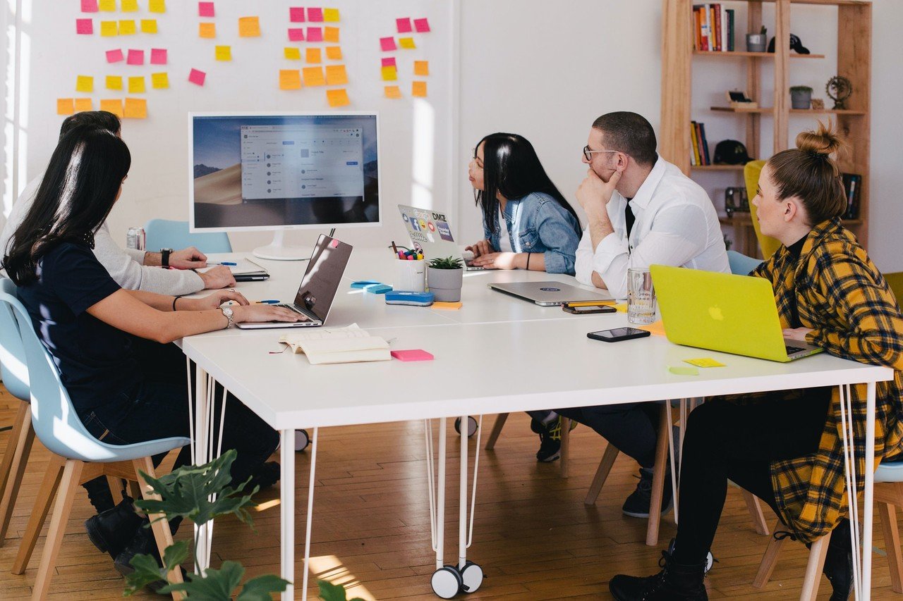 Teammitglieder, die mit ihren Laptops und Haftnotizen an der Wand zusammenarbeiten