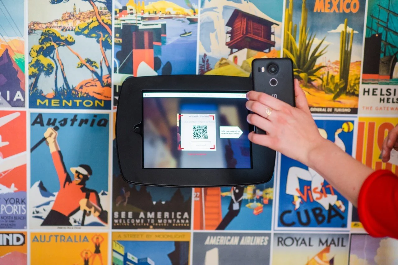 uma pessoa digitalizando um código QR com um smartphone preto e um fundo de ilustrações de diferentes países